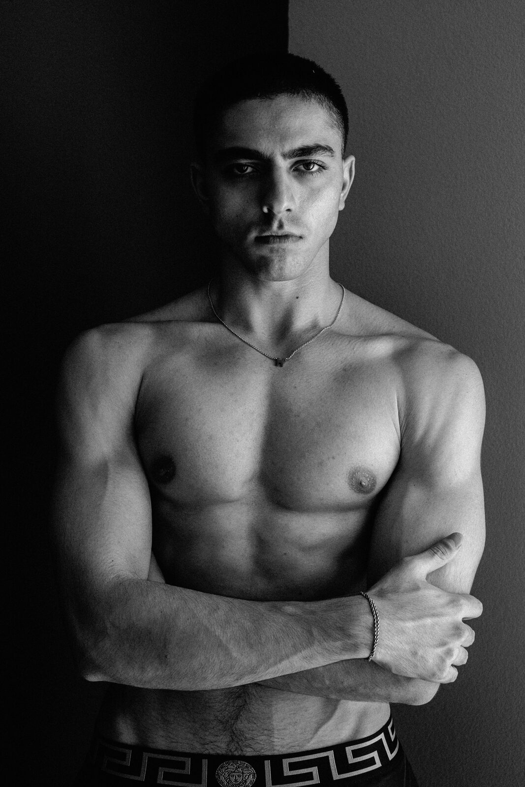Black and white studio portrait of male model with arms crossed, by Tony Liam